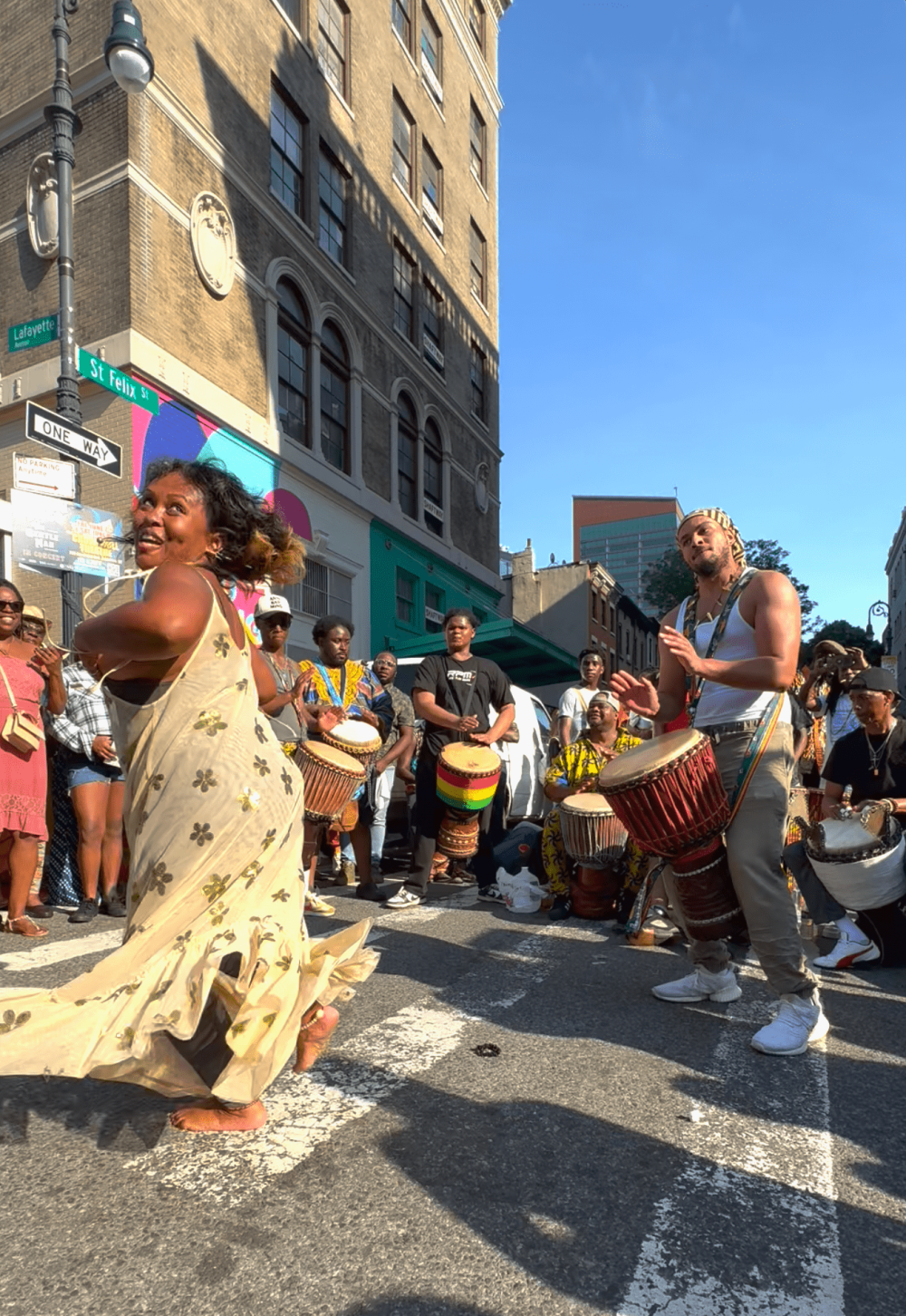 Joyous woman in a flowing dress dances energetically on St.Felix Ave.