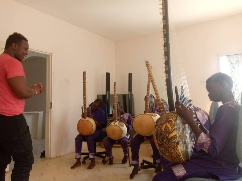 A teacher guides students in learning the kora, the 21-string harp central to the West African griot tradition.