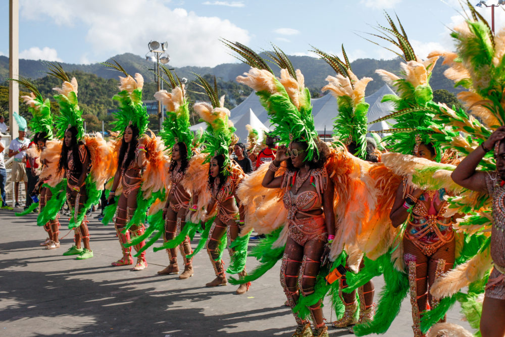 Masqueraders in feathers wait on the stage