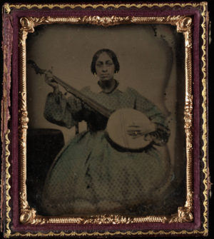 Portrait of a young black woman seated holding nine string banjo